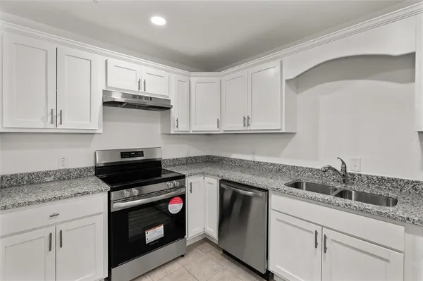 a kitchen with granite countertop white cabinets and stainless steel appliances