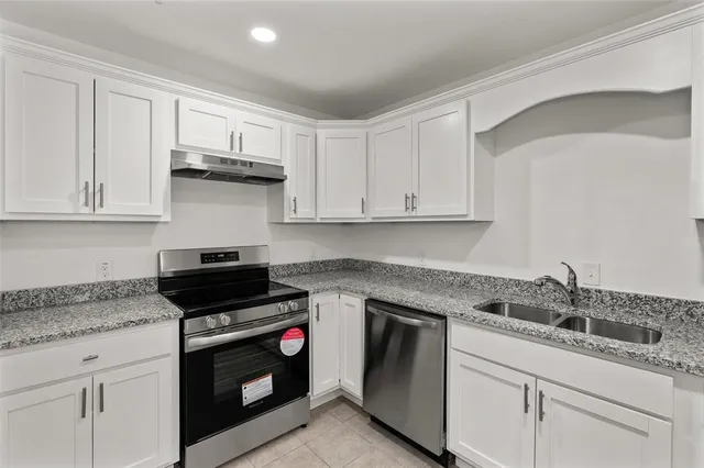 a kitchen with granite countertop white cabinets and stainless steel appliances