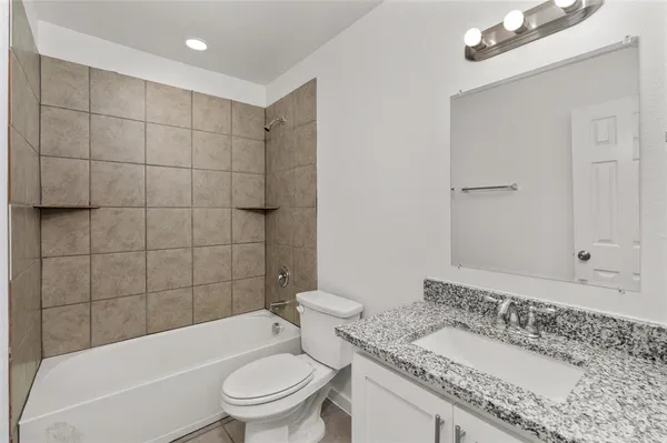 a bathroom with a granite countertop sink a toilet and bathtub