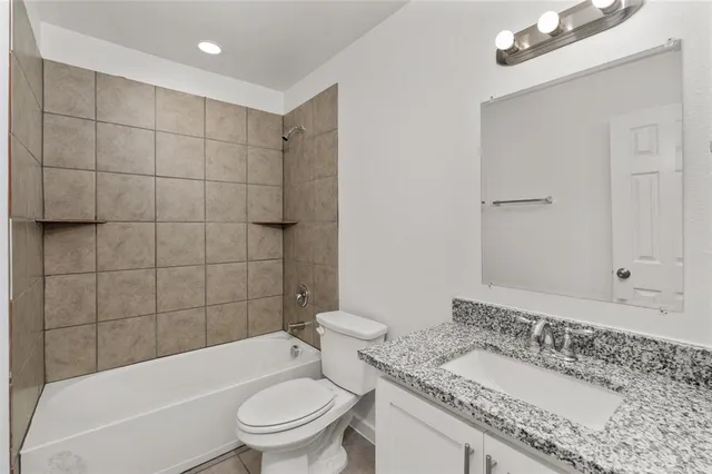 a bathroom with a granite countertop sink a toilet and bathtub