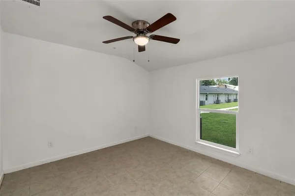 an empty room with ceiling fan and window