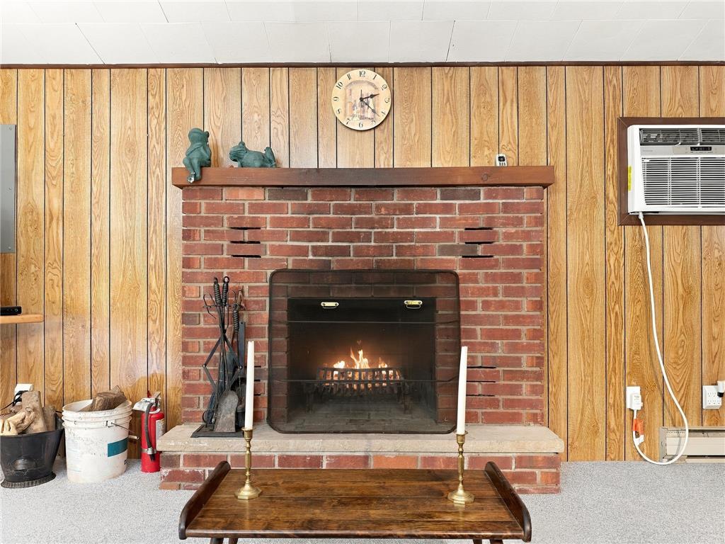 116 Aspen Road Albrightsville, PA 18210 - Photo 14 of 33 A classic brick fireplace anchors the wood-paneled wall, creating a cozy and warm atmosphere.