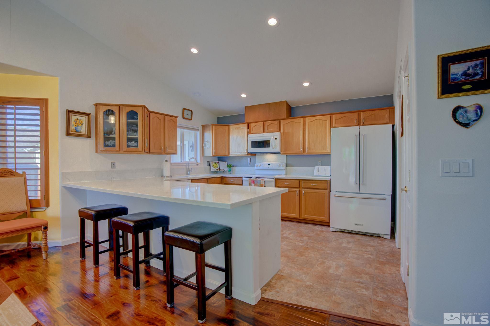 1315 Wrangler Circle Minden, NV 89423 - Photo 11 of 40 a kitchen with stainless steel appliances granite countertop a refrigerator a sink a stove a dining table and chairs with wooden floor