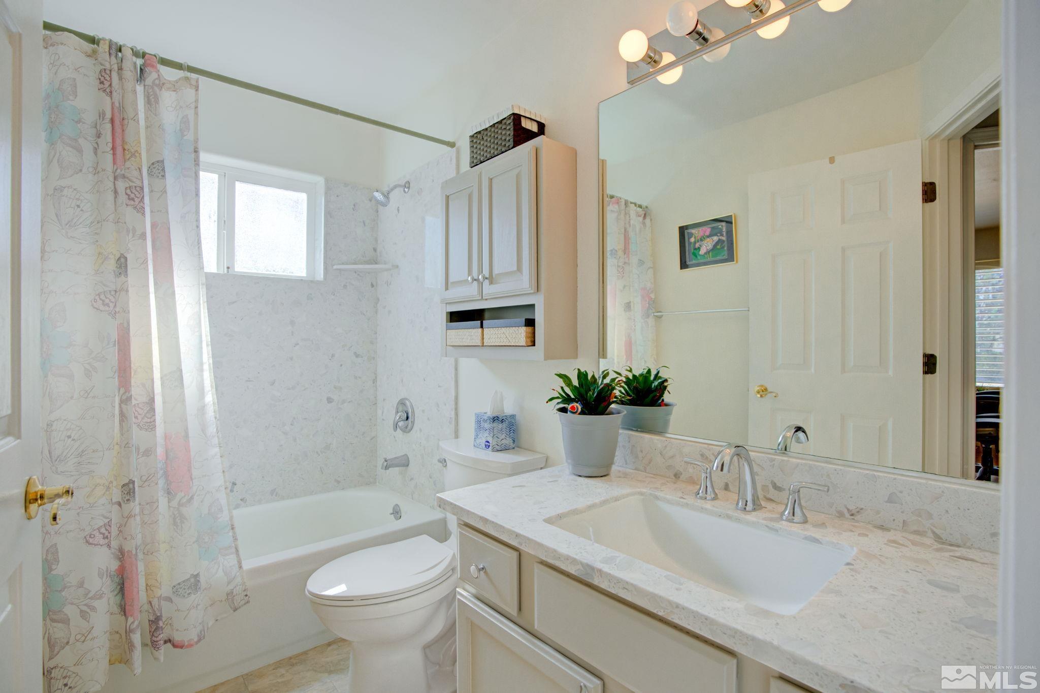1315 Wrangler Circle Minden, NV 89423 - Photo 24 of 40 a bathroom with a granite countertop sink a toilet a mirror a vanity and shower