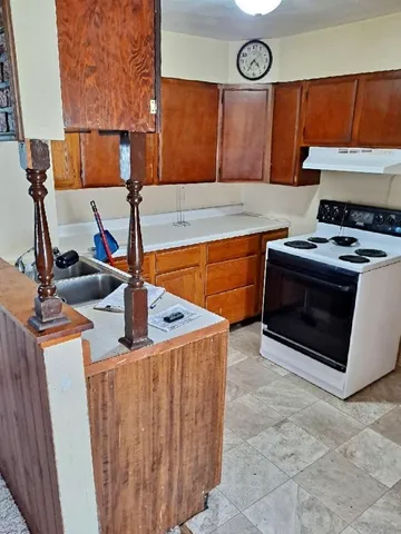 a kitchen with stainless steel appliances granite countertop a stove and a sink with wooden cabinets