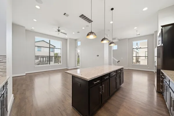 a kitchen with a stove center island wooden floor cabinets and a window