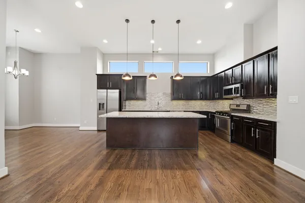 a large kitchen with stainless steel appliances granite countertop a stove a refrigerator a sink dishwasher and a oven with wooden floor