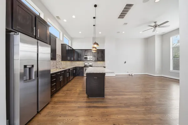 a large kitchen with stainless steel appliances kitchen island a large counter top and wooden floors