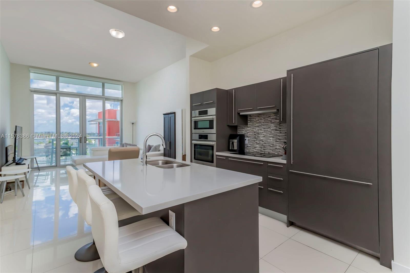 a large kitchen with kitchen island a large window a sink and stainless steel appliances