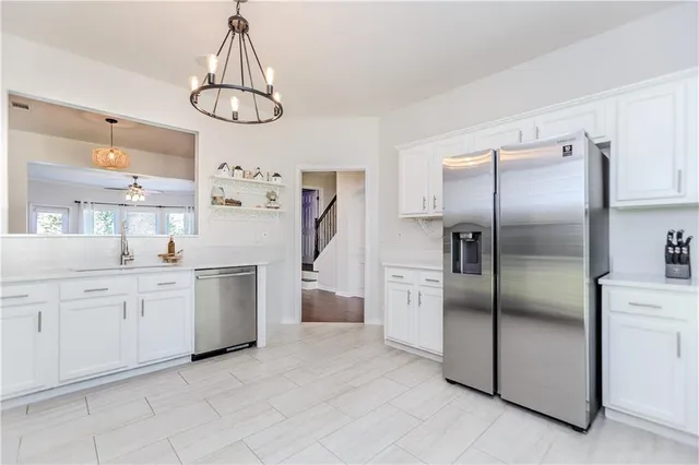 a kitchen with white cabinets stainless steel appliances and a chandelier