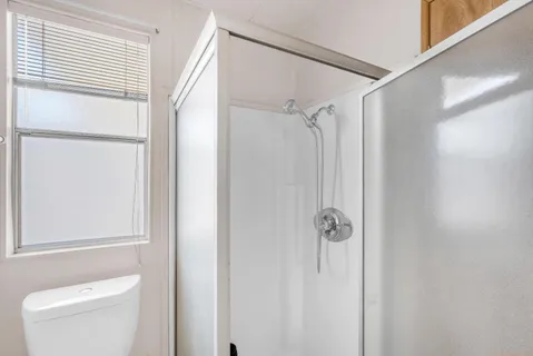 a bathroom with a shower a toilet and a window