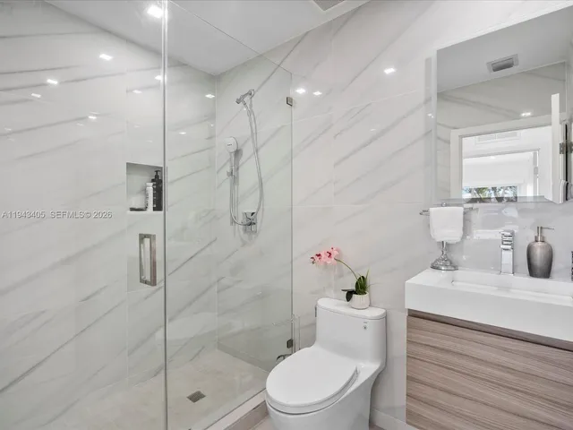a bathroom with a sink toilet vanity and shower