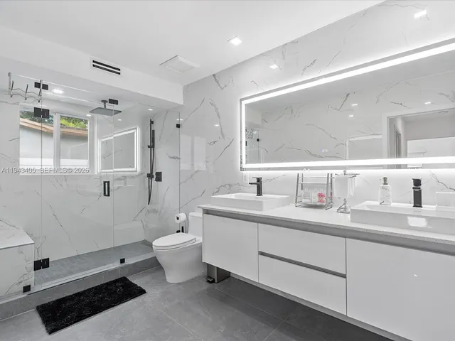 a bathroom with a double vanity sink toilet mirror and bathtub