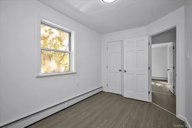 an empty room with wooden floor closet and windows