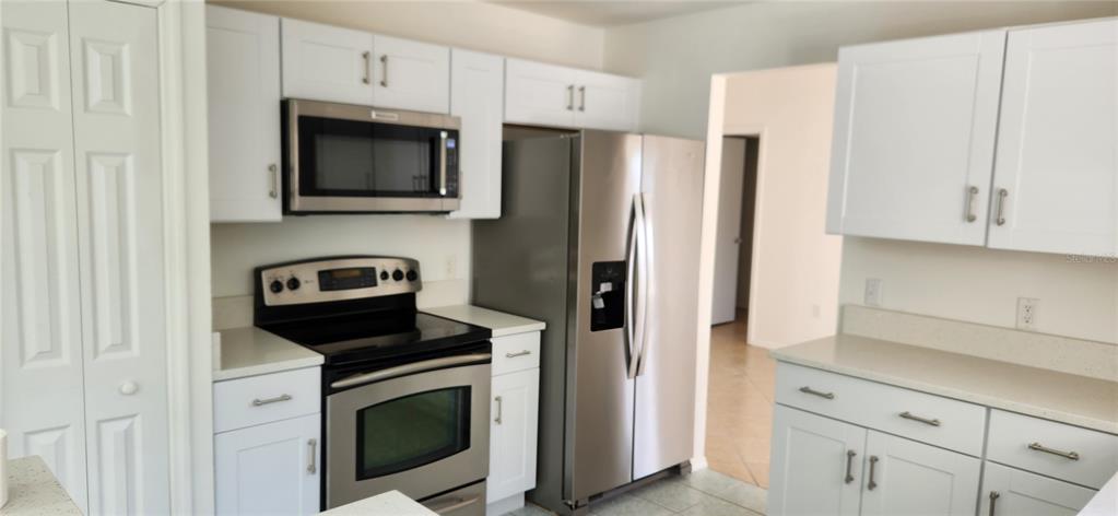 2856 Trenton Lane Deltona, FL 32738 - Photo 2 of 16 a kitchen with stainless steel appliances white cabinets white stove a refrigerator and a microwave