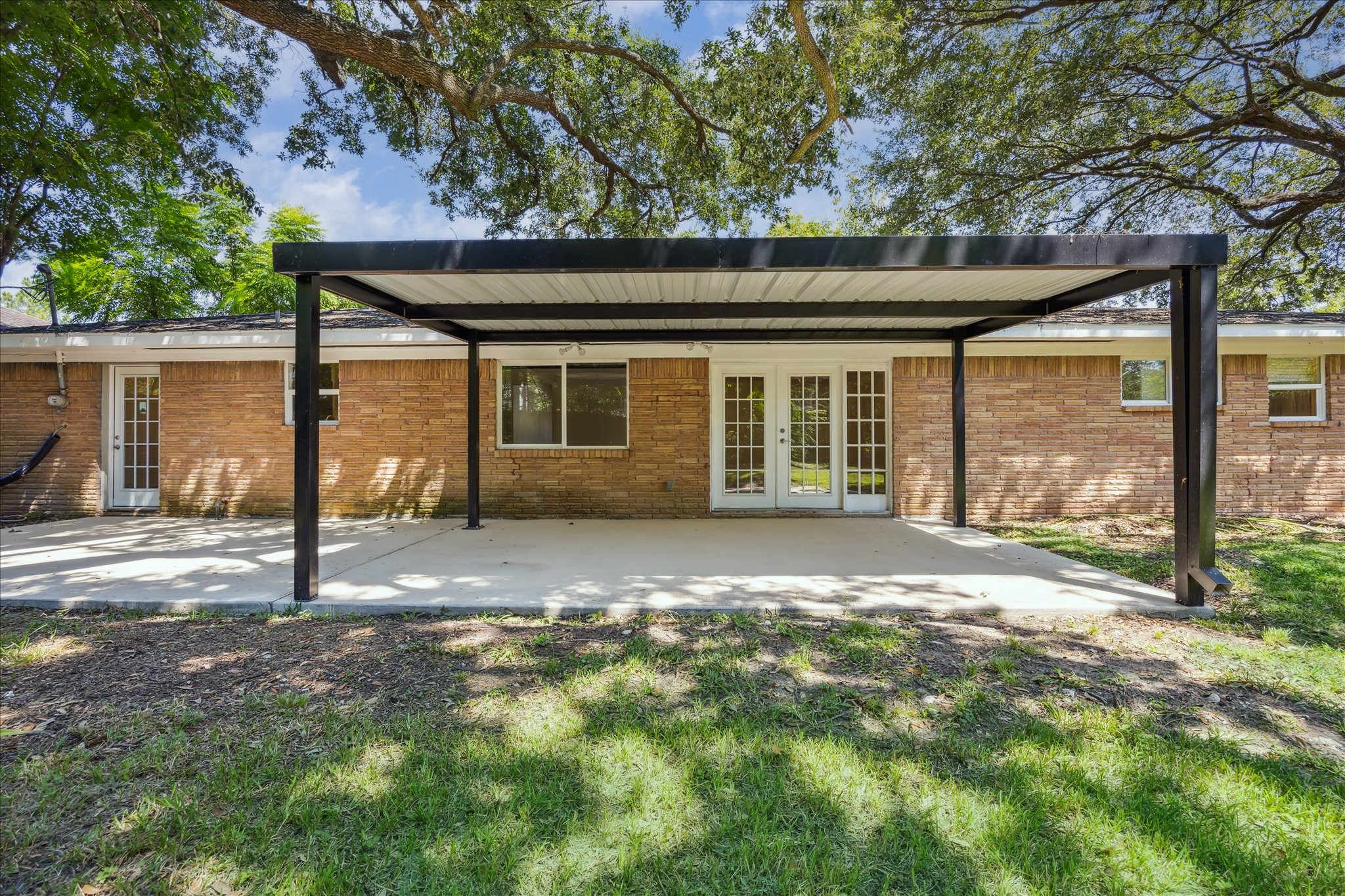 5419 Beechnut Street Houston, TX 77096 - Photo 24 of 28 Rear view of the home highlights the wide covered patio and French doors, seamlessly blending indoor and outdoor living.