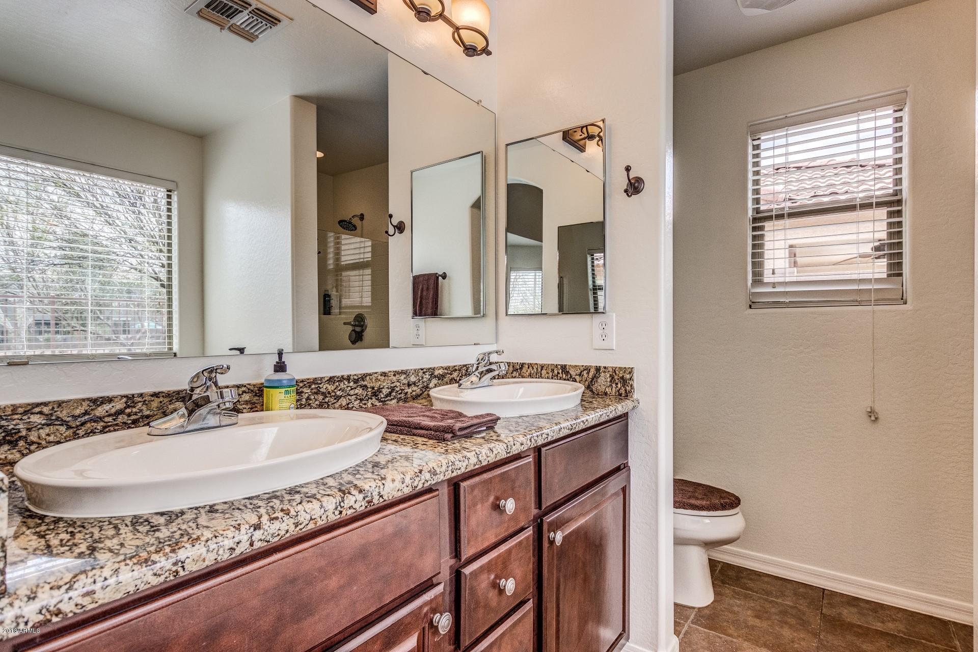 3927 East Blue Sage Road Gilbert, AZ 85297 - Photo 12 of 26 a bathroom with a granite countertop sink a toilet and a mirror