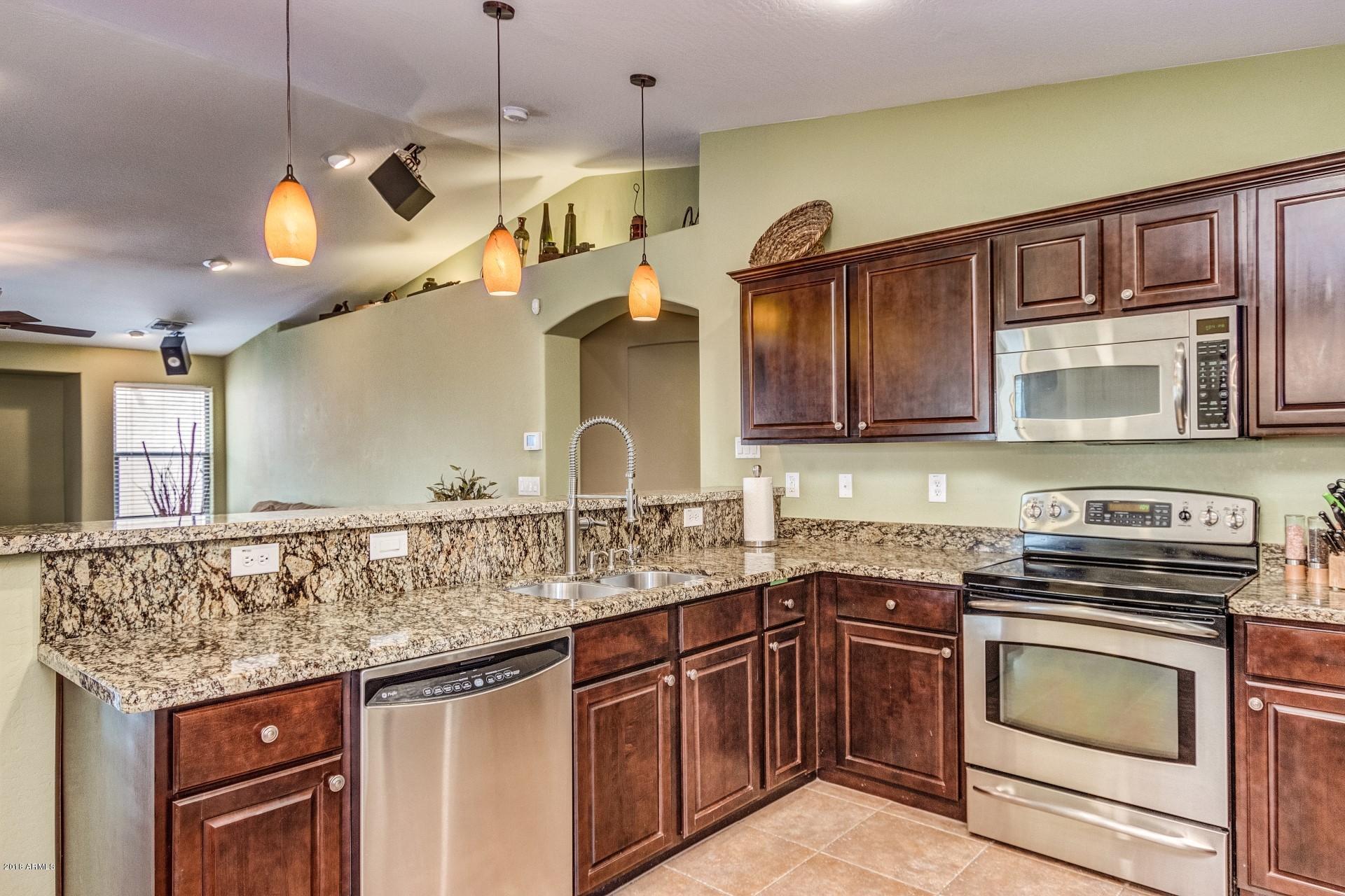 3927 East Blue Sage Road Gilbert, AZ 85297 - Photo 3 of 26 a kitchen with stainless steel appliances granite countertop a sink and stove top oven