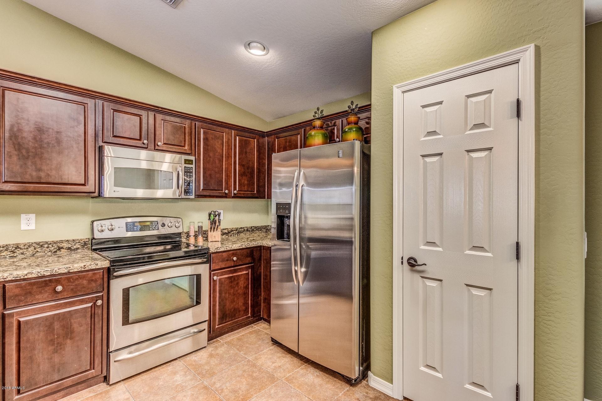 3927 East Blue Sage Road Gilbert, AZ 85297 - Photo 5 of 26 a kitchen with stainless steel appliances granite countertop white cabinets and refrigerator