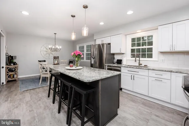 a kitchen with kitchen island granite countertop a sink and a refrigerator
