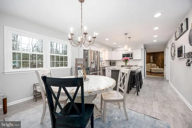a view of a dining room and livingroom with furniture a rug a fireplace and a chandelier