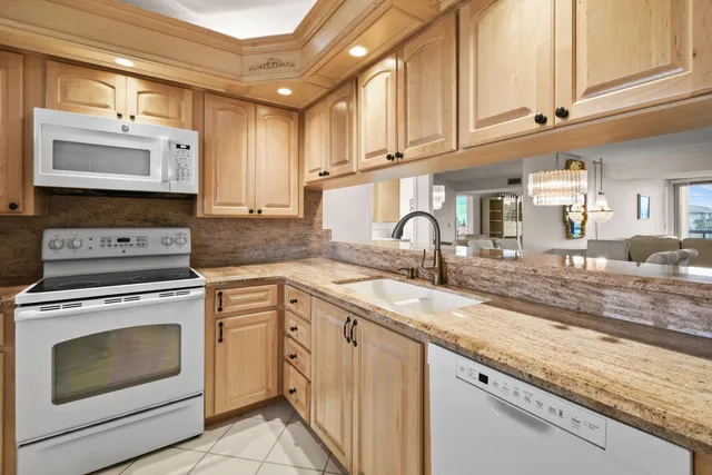 a kitchen with stainless steel appliances granite countertop a refrigerator a stove a microwave a dining table and chairs