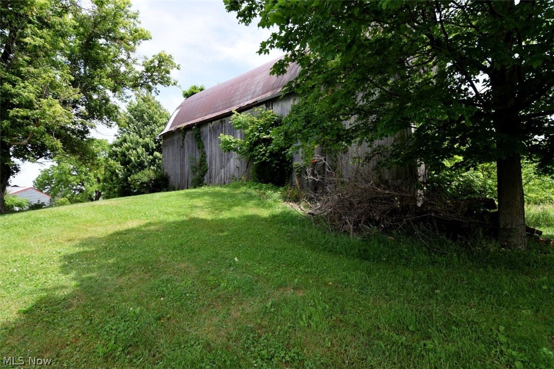7251 Ryan Road Medina, OH 44256 - Photo 38 of 47 Weathered barn with a corrugated metal roof, surrounded by mature trees and a grassy slope