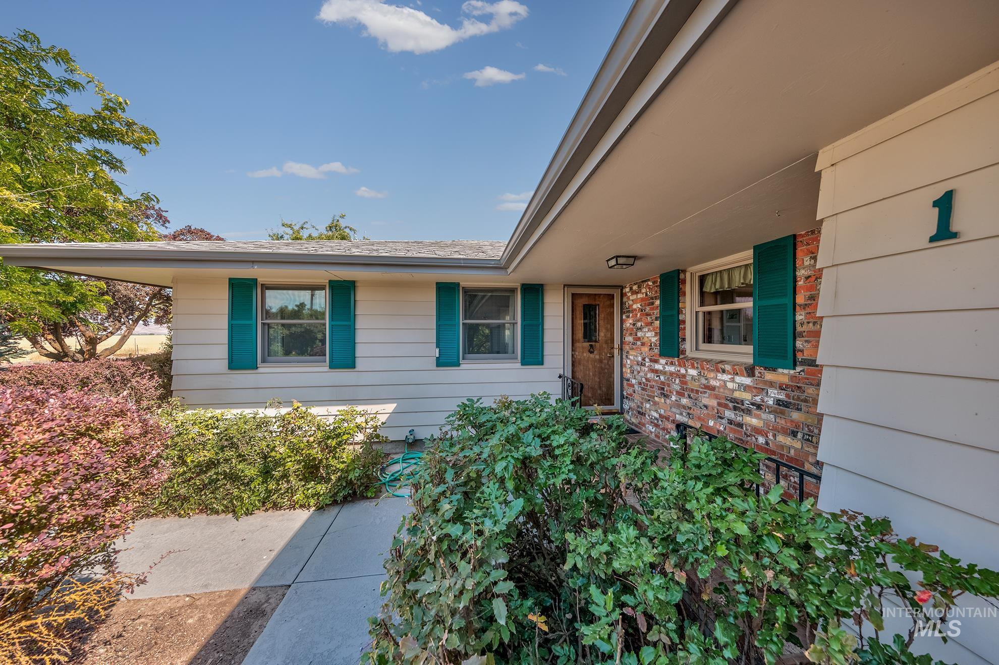 1493 Cove Road Weiser, ID 83672 - Photo 4 of 50 Exterior featuring horizontal siding, brick accents, and teal window shutters