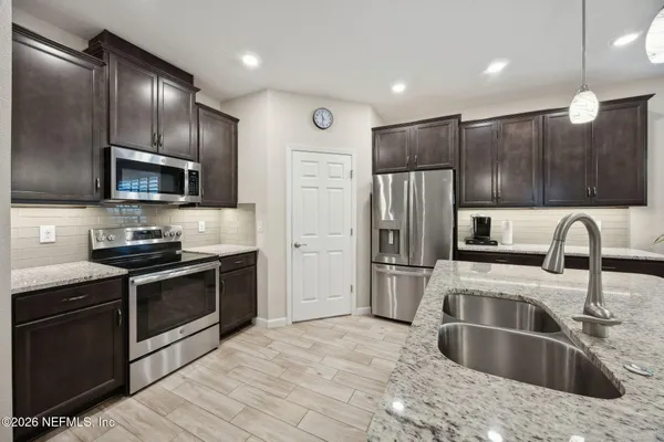 a kitchen with stainless steel appliances wooden cabinets a sink dishwasher a refrigerator and a oven with wooden floor