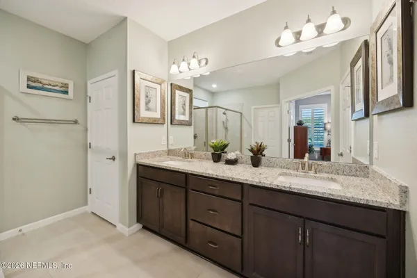 a bathroom with a granite countertop double vanity sink and a mirror