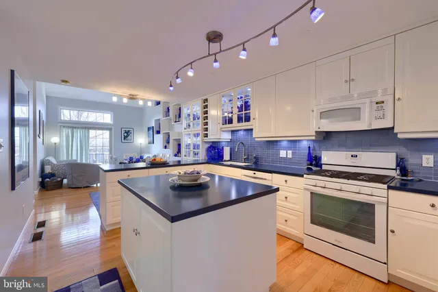 a kitchen with kitchen island a stove a sink a refrigerator and chairs