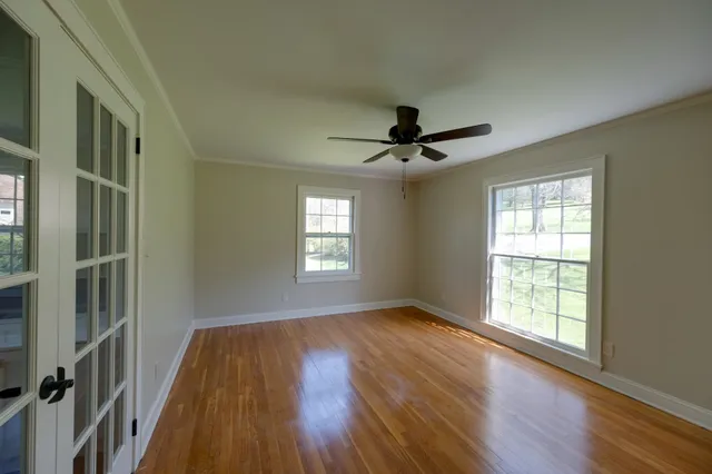 a view of an empty room with wooden floor and a window
