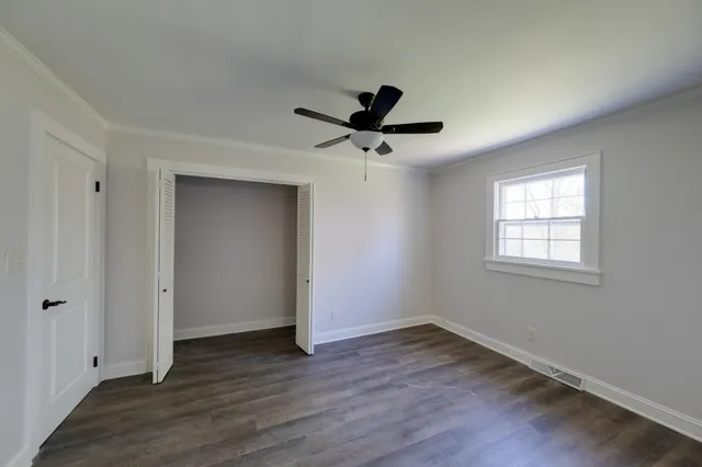 a view of empty room with wooden floor and fan