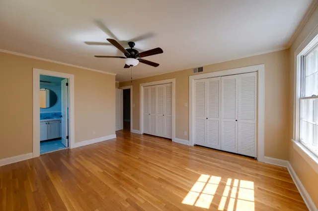 a view of empty room with wooden floor and ceiling fan