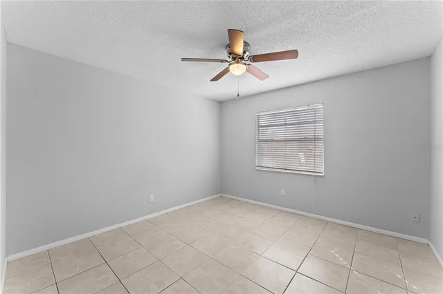an empty room with a ceiling fan and carpet