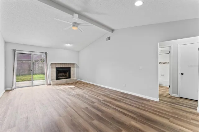 a view of empty room with wooden floor and fireplace