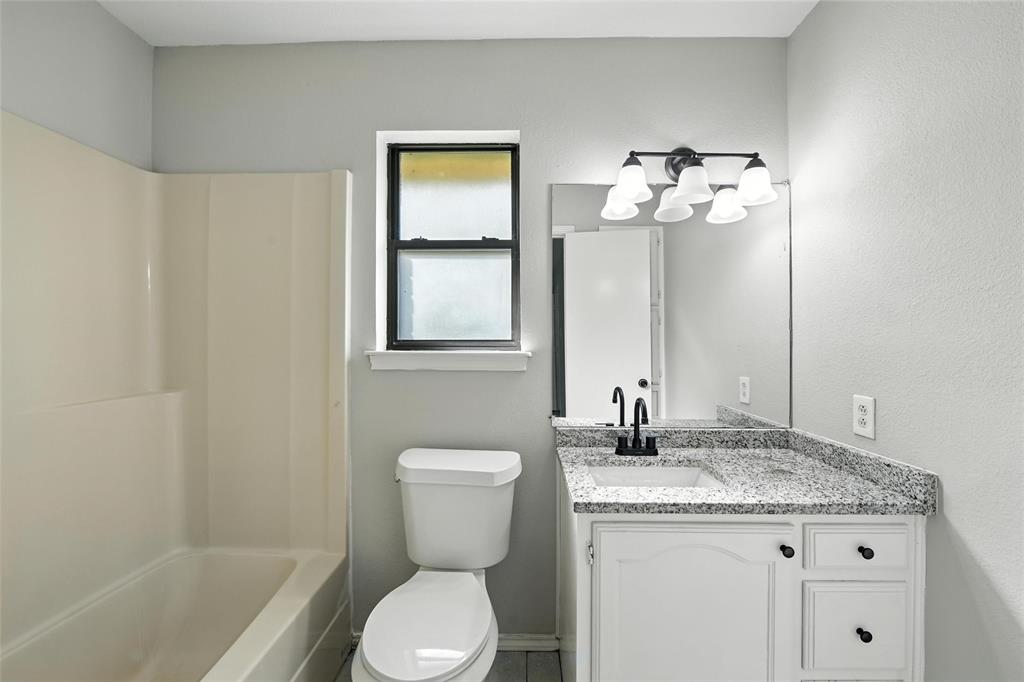 602 Valleyridge Court Decatur, TX 76234 - Photo 22 of 27 a bathroom with a granite countertop sink a toilet and a mirror