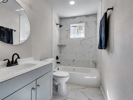 a bathroom with a tub sink toilet and mirror
