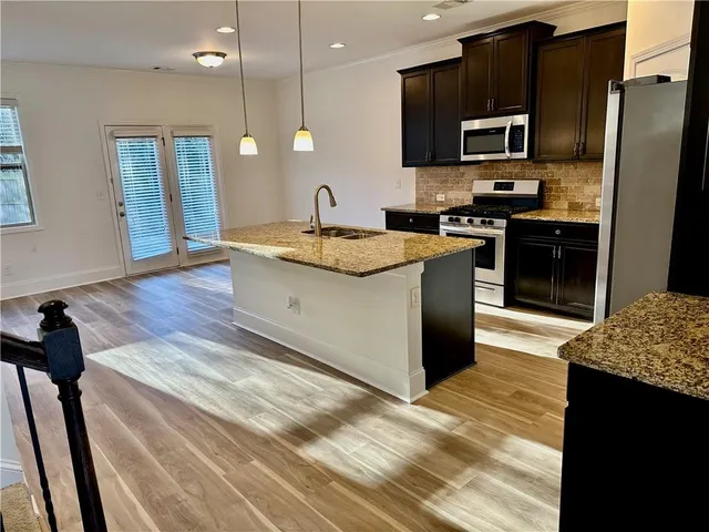 a kitchen with kitchen island granite countertop a sink and a stove