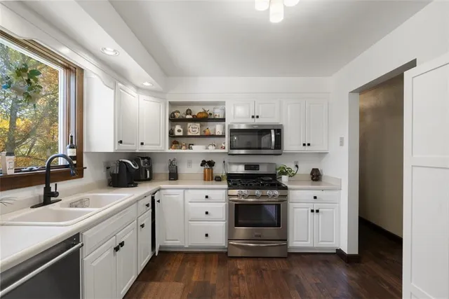 a kitchen with stainless steel appliances a sink stove and wooden floor