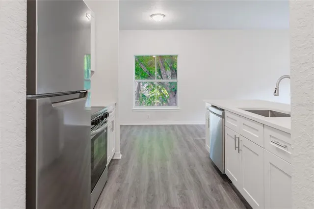a sink with white cabinets and a wooden floor