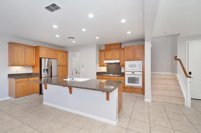 a view of kitchen with stainless steel appliances granite countertop refrigerator and stove