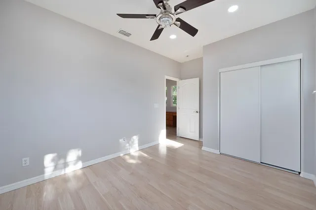 an empty room with a ceiling fan and wooden floor