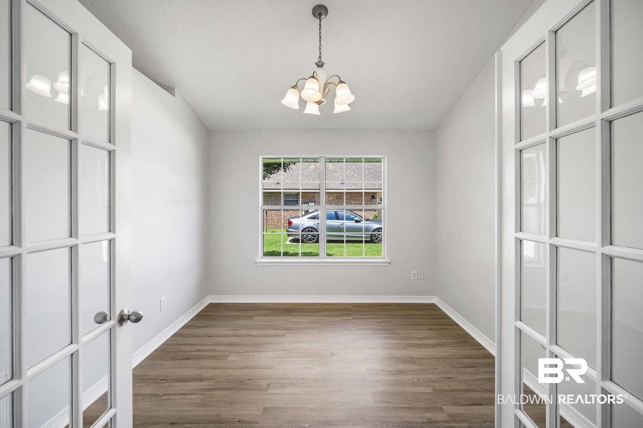 9814 Woolrich Avenue Fairhope, AL 36532 - Photo 12 of 29 Empty room with hardwood / wood-style floors and an inviting chandelier