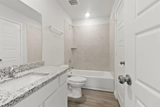 a bathroom with a granite countertop sink a toilet and shower