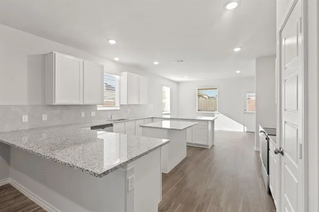 a large kitchen with stainless steel appliances granite countertop a lot of counter space and wooden floors