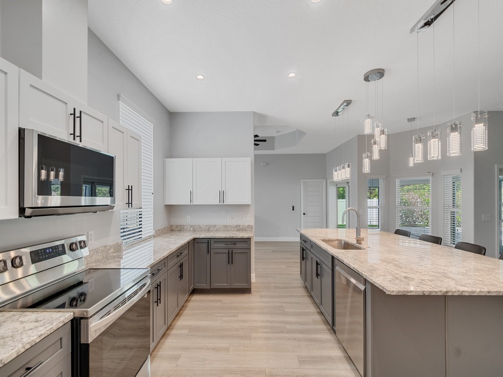 431 Midvale Terrace Sebastian, FL 32958 - Photo 16 of 34 a large kitchen with stainless steel appliances kitchen island granite countertop a large stove top oven and cabinets