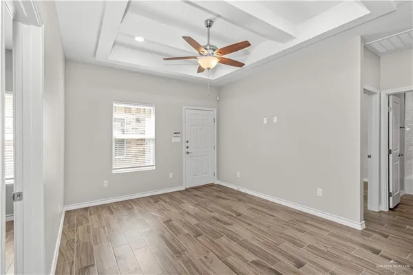 a view of kitchen and empty room with wooden floor