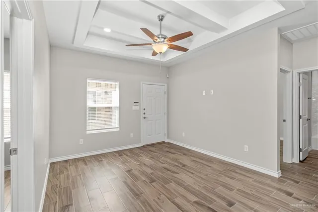 a view of kitchen and empty room with wooden floor
