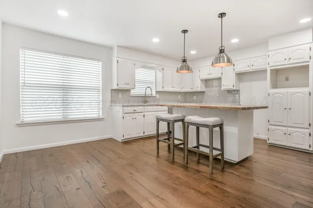 a kitchen with stainless steel appliances granite countertop white cabinets a stove a sink and a wooden floors